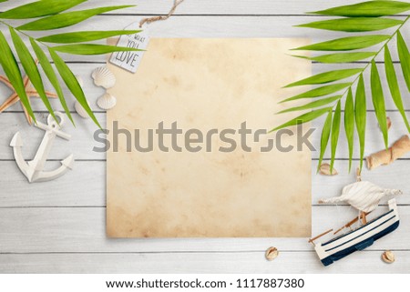 Old paper on white wooden background surrounded with summer holiday decoration. Palm leaves, seashells, anchor, starfish and boat. Empty space for text, travel concept