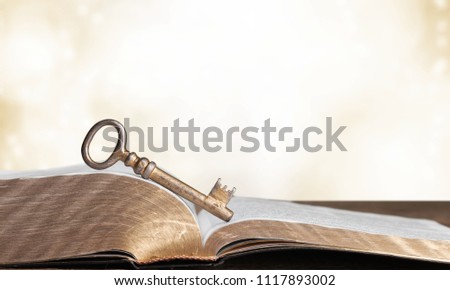 Close-up of opened book pages and key against vintage background