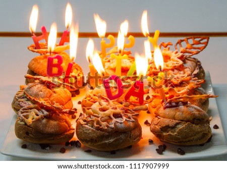 happy birthday choux cream with candles on table on white plate