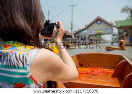 Tourist in Thailand visiting floating market taking photo using camera, sightseeing in Bangkok.