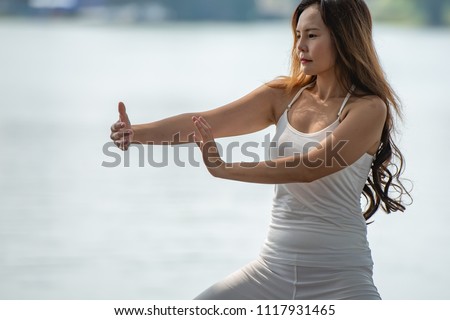 Young woman doing traditional Tai Chi Chuan, Tai Ji and Qi gong in the park for healthy, traditional Chinese martial arts concept. Royalty-Free Stock Photo #1117931465