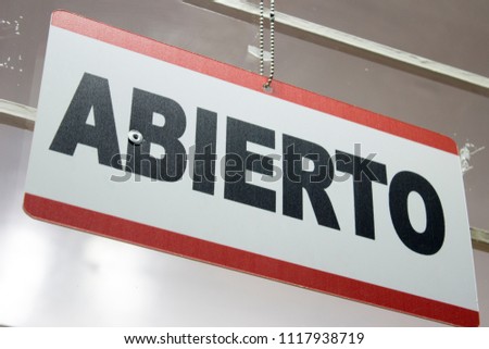 An spanish open sign hanging in a store. Abierto meaning open.