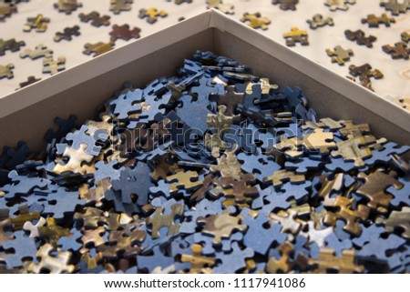 Blue jigsaw puzzle in a box, with pieces ordered face-up around it.