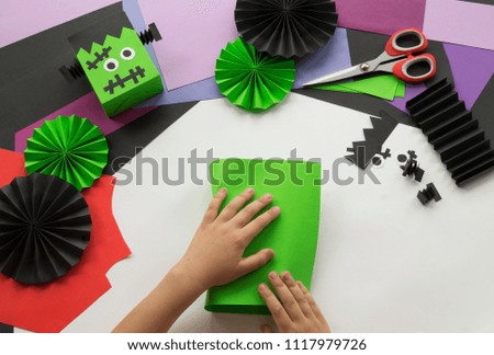 The child makes crafts for a Halloween party. Children's hands master class. Green monster. A terrible craft. School and kindergarten.