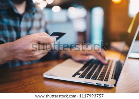 Man’s use credit card and laptop for shopping on wooden table at coffee shop. Online shopping, online payment. Royalty-Free Stock Photo #1117993757