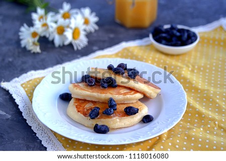 Oatmeal pancakes with honey and berries on a dark gray concrete background