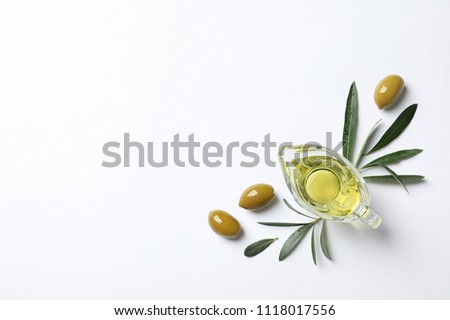 Gravy boat with oil and ripe olives on white background