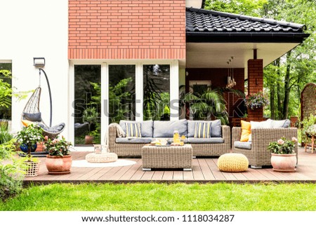 Real photo of a beautiful terrace with garden furniture, plants and swing