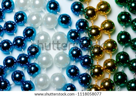 Bright colorful macro abstract of multicolor Mardi Gras bead necklaces with bokeh, arranged in a row pattern design with white background
