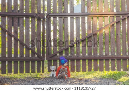 girl, child at the fence, with a toy dog at sunset
