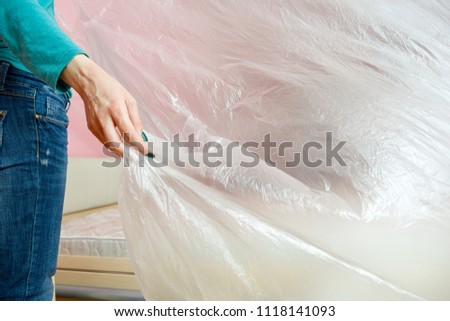 Photo of young woman covering bed with polyethylene