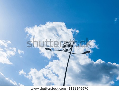Lamp post in the form of a ball, against the blue sky with clouds