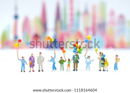 miniature figure people : Happy family  catch balloons standding on white floor with blur city blackgroung. Picture use for holliday concept, family concept or international day of families.