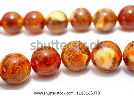 Amber. Beads made from natural yellow brown amber mineral on a white background. Fashionable jewelry amber beads from round and oblong beads. Sun stone as a jeweler raw material. Frozen Resin Fossil Royalty-Free Stock Photo #1118165378