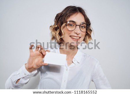 woman with wavy hair and with glasses holds a badge in her hand                              