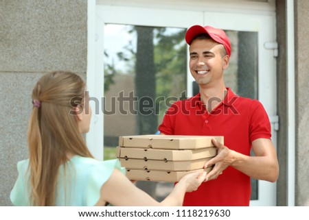 Young man giving pizza boxes to woman outdoors. Food delivery service