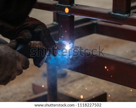 Worker is weld metal with a arc welding machine at the construction site. blue sparks fly to the sides. Industrial steel welder in factory technical. welder Industrial in factory