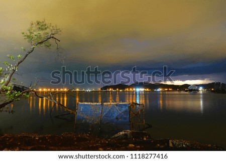 Long exposure night view shot at Songkhla Lake Southern Thailand before rain,colored sky and clouds after sunset and reflection water before rain background,Selective focus.