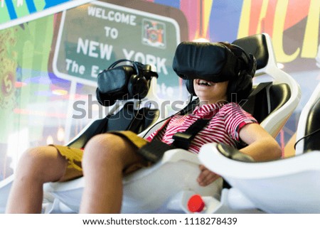 Amazed teen boy screaming, wearing virtual reality goggles watching movies, siting in 4D chair.
