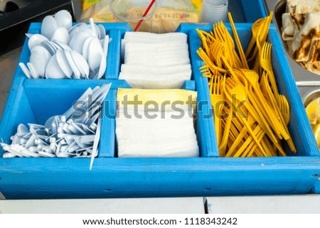 Disposable plastic forks and spoons with napkins in a blue wooden box