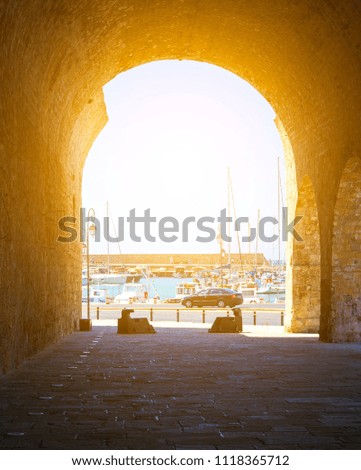 An ancient Arch in Heraklion, the capital of Crete. The white ships moored to the coast of the Mediterranean Sea are in the distance visible