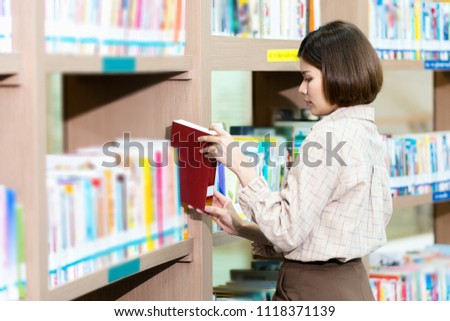 Young female student study in the school library. She is searching for knowledge in the library.