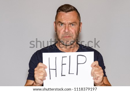 Middle-aged man holding white sheet of paper with help lettering