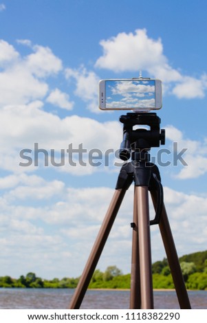 Using smartphone like professional camera on tripod to capturing landscape with blue sky and river