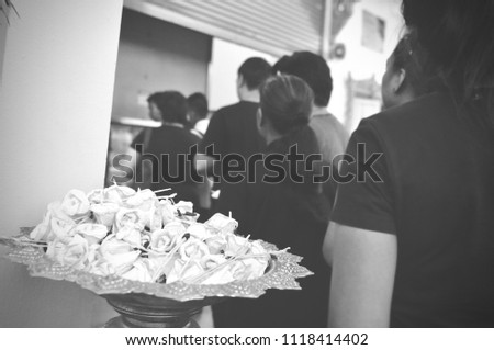 B&W photo of people and Sandalwood flowers or artificial flowers or wood cremation flower, kind of wood flower to be placed on the site of cremation or used during a funeral