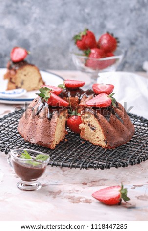 Bundt cake with melted chocolate and fresh strawberries. Top view