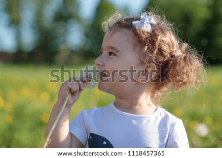 little baby girl with dandelion in the field