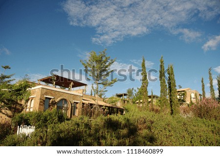Brick house in Italian style. There are trees around the house. blue sky