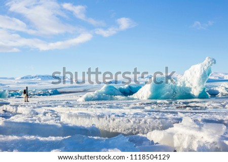 Man above a sheet of ice watching a big iceberg in Jökulsárlón glacial lagoon, Vatnajökull National Park, southeast of Iceland, Europe.
