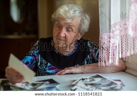 An elderly woman watching photos sitting at the table.