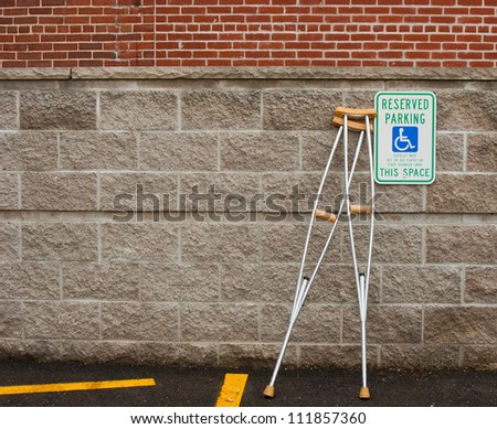 pair of crutches leaning next to a handicapped parking sign
