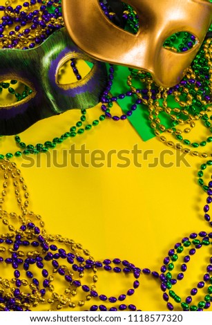 Two Mardi Gras mask with colorful beads on a yellow background