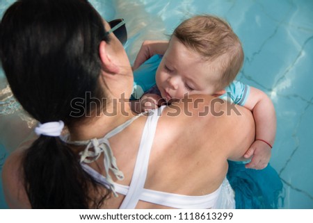 Closeup portrait of cute little baby sleeping on mothers shoulder in the pool, happy young loving family, new life concept