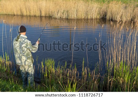 A man on a summer fishing with fishing rods and gear catches a pike fish