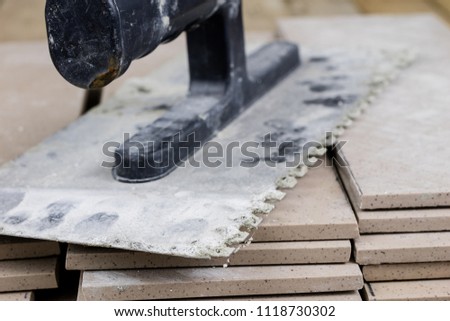 Tiles for laying on the floor. Accessories and material for a construction worker arranged on a wooden workshop table. Dark background