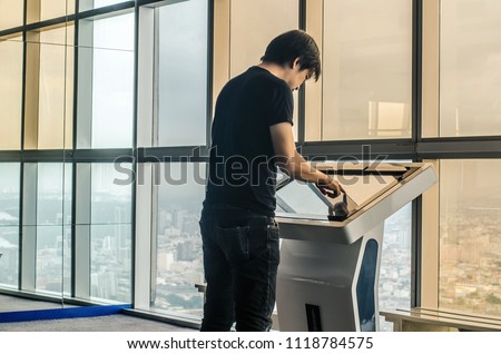 Attractive young man standing front big digital screen with basic tower map data, male touching sensitive display of modern smart building stop for check her location.