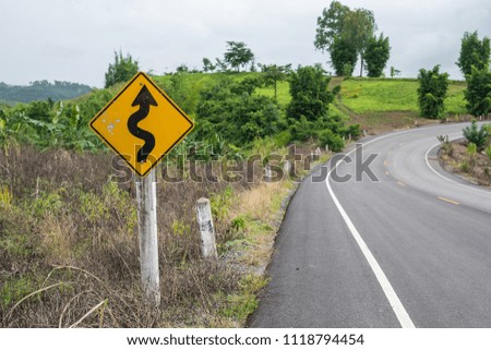 Road curve with traffic sign. Road curve to mountain. Traffic sign on road curve in country