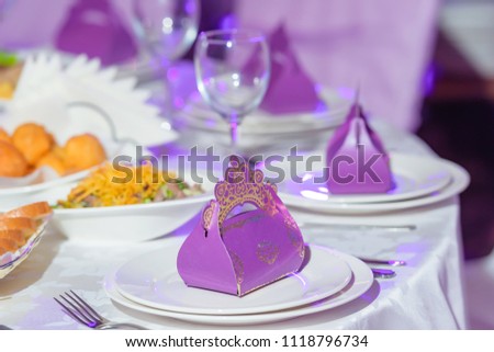 Violet bonbonniere on the festive table. Decoration of a banquet table in color Panton. Gift boxes with sweets