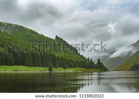 View of a beautlful lake Talla in Scottish borders with green hills covered by thick rainy clouds.