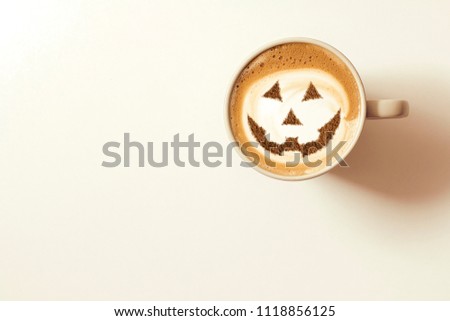 a cup of cappuccino coffee with a picture of a halloween symbol from cinnamon on milk foam