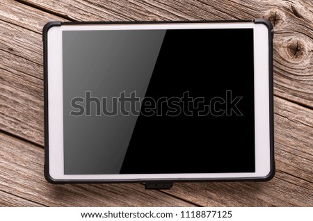 White tablet computer on old wood table background.