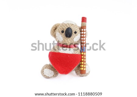 Souvenir from Australia isolated on white background. Koala bear in aboriginal outfit and musical instrument called Didgeridoo. 