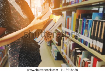 Close up hand of librarian or woman or Students holds books beside and taking book from bookshelf at university or National Library. education ,lifestyle ,Search for information and people concept