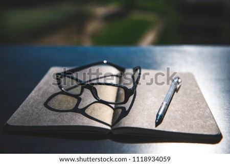 Office concept: notebook, pen and glasses on the table on street background. Desktop office, business office desk