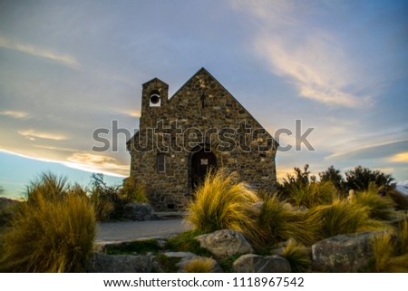 Amazing sunset at the most beautiful Church Of The Good Shepherd by Lake Tekapo, South Island, New Zealand. Dramatic sky, evening light, snowy mountains on the background. Warm colours. Winter.