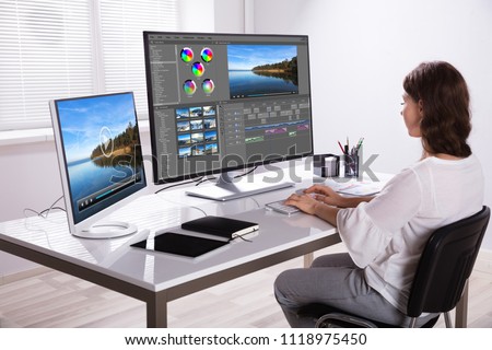 Young Female Editor Editing Video On Computer In Office Royalty-Free Stock Photo #1118975450